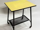 une petite table avec un plateau jaune et des pieds noirs