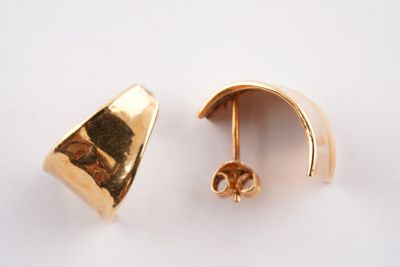 deux paires de boucles d'oreilles en or posées sur une surface blanche
