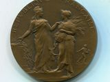médaille de bronze représentant deux femmes et un chien sur un fond blanc