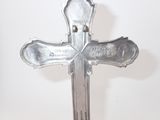 a metal cross on a stand on a white surface