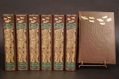 Quatre livres marron aux tranches dorées sont alignés sur une surface noire