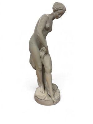 statue d'une femme penchée en avant sur une surface blanche, avec un fond blanc