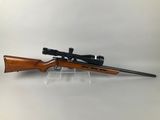 a rifle with a scope on a clear stand