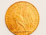 a gold coin with a rooster on it on a white surface