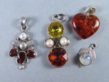 quatre pierres de couleurs différentes et des breloques en argent sur un fond blanc