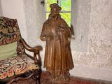 une statue représentant un homme debout à côté d'une chaise dans une pièce