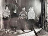 three boys walking down a narrow street at night