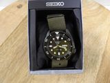 a black and green watch in a box on a wooden table