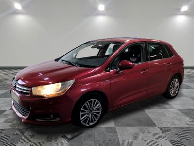 une voiture rouge est garée dans une pièce au sol en damier