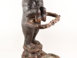 a statue of a bear holding a bowl on a tree stump
