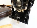 an old camera sitting on top of a table next to a purse
