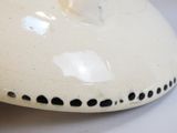 un vase blanc parsemé de points noirs, posé sur une table