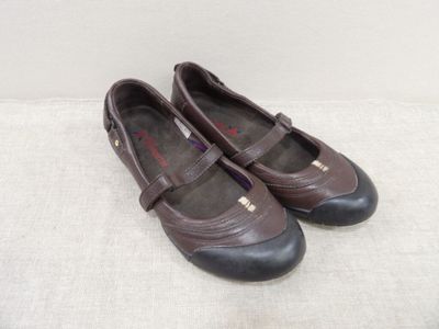une paire de chaussures pour femme, marron et noires, posées sur une surface blanche