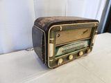 an old radio sitting on a table with a curtain behind it