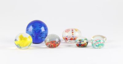 Plusieurs billes de verre sont alignées sur une surface blanche
