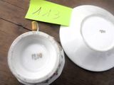 une tasse et une soucoupe posées sur une table, avec un mot accroché dessus