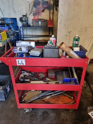 un chariot de chantier rouge chargé d'outils, dans un garage