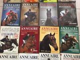plusieurs livres posés par terre dans une pièce, sur lesquels figurent des chevaux et des jockeys