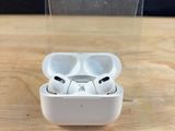 des AirPods de la marque Apple posés sur une table en bois, à côté d'une boîte transparente