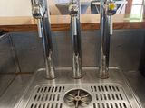 a metal sink with a bunch of beer taps on it