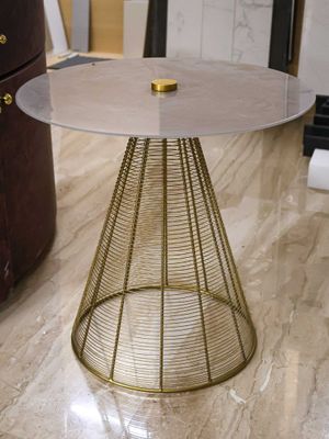 a table that has a glass top and a gold base