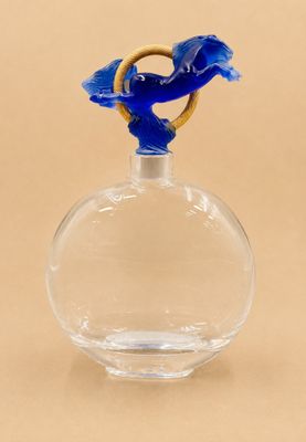 un oiseau bleu perché au sommet d'une bouteille en verre transparent