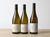 trois bouteilles de vin sont alignées sur une table en bois