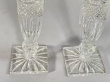 two clear glass candlesticks sitting next to each other