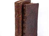 an old book with a leather cover sitting on a white surface