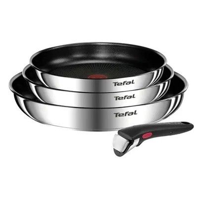 trois casseroles en acier inoxydable et une spatule sur fond blanc
