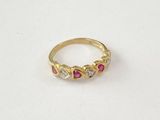gros plan d'une bague en or avec des pierres roses et blanches