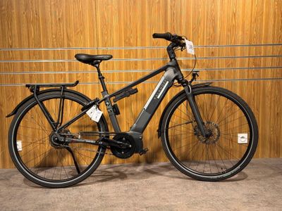 un vélo noir garé dans un garage, à côté d'un mur en bois