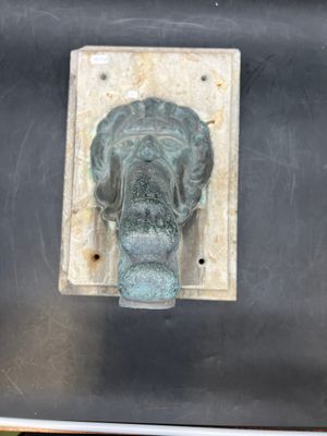 an image of a bronze elephant head on a metal plate