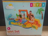 une piscine gonflable avec un toboggan aquatique et une famille assise dessus