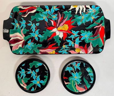 un plateau noir orné d'un motif floral et deux dessous de verre assortis