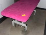 un lit rose dans une chambre où se trouve une chaise noire