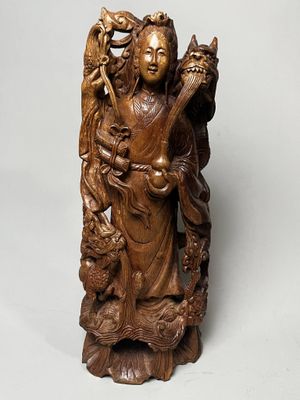 statue en bois représentant une femme tenant un chat et un oiseau perché sur une branche