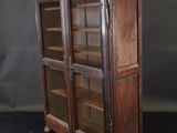 an old wooden bookcase with glass doors on a black background