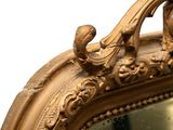 a gold mirror with a bird on top of it