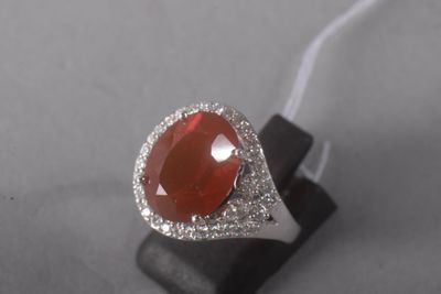 an image of a ring with a red stone surrounded by white diamonds