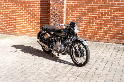 a black motorcycle parked on a brick sidewalk in front of a brick building