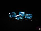 a close up of three pieces of blue topazte on a black surface