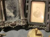 two antique picture frames and a candle holder on the table