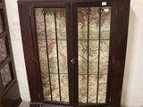 a cabinet with a glass door in the corner of the room