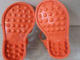 pair of orange rubber shoes with holes on them sitting on a couch
