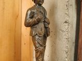 a statue of a man standing on a wooden shelf