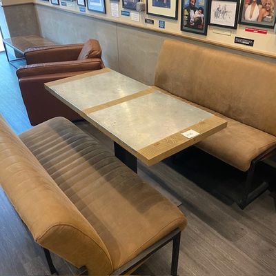 un banc et une table dans une pièce où sont accrochés des tableaux au mur