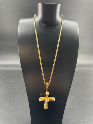 un pendentif en forme de croix en or avec une chaîne, posé sur un mannequin