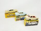 three toy cars are sitting on top of boxes on a white surface
