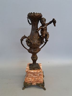 a bronze vase on a marble base with two cherenshes on it